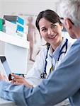 Doctor sharing health information on digital tablet with patient in clinic