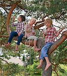 Group of young friends sitting in tree, drinking bottled drinks