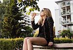 Young woman sitting outdoors, drinking from water bottle