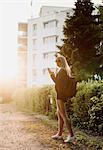 Young woman outdoors, walking along street, using smartphone