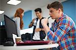 Young male college student at computer desk looking at computer