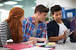 Young female and two male college students teamworking at desk