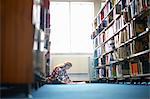 Young female college student working on library floor