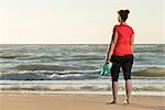 Mature woman standing on beach at sunset, after running