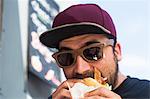 Male customer eating hamburger from fast food van
