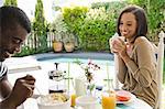 Young couple sharing eating breakfast together by swimming pool