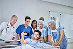 Patient in hospital bed taking selfie with doctors and nurses