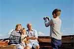 Boy photographing grandparents and brother on boat