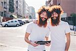 Portrait of young male hipster twins with red hair and beards  on city street