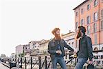 Young male hipster twins with red hair and beards talking on canal waterfront