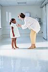 Female doctor using stethoscope on girl in hospital children's ward