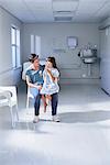 Girl patient sitting on her mothers lap in hospital children's ward