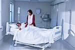 Girl patient in bed tended by her mother on hospital children's ward