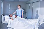 Nurse tending girl patient in bed on hospital children's ward