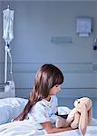 Girl patient gazing at toy rabbit on hospital children's ward