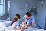 Nurse and girl patient playing with toy rabbit on hospital children's ward