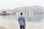 Young man looking out from lakeside, Lake Como, Italy
