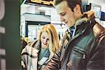 Young couple buying train tickets from ticket machine