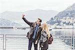 Young couple on lakeside taking smartphone selfie, Lake Como, Italy