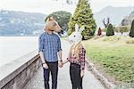 Couple wearing horse and rabbit masks holding hands, Lake Como, Italy