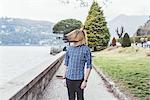 Portrait of man wearing horse mask looking out at  Lake Como, Italy