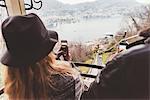 Over the shoulder view of couple on funicular photographing Lake Como, Italy