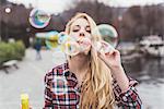 Portrait of young woman on waterfront blowing bubbles,  Lake Como, Italy