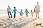 Rear view of family on beach holding hands