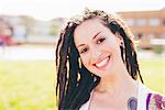 Portrait of tattooed young woman with dreadlocks in urban park