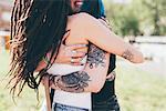 Tattooed young women hugging in urban park