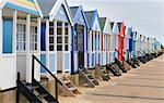 Angled view of a row of multi-coloured beach huts, Southwold, Suffolk, UK