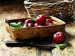 Organic plums in vintage basket, rustic wooden table, vintage knife
