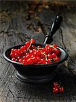 Red currants in small vintage metal sieve, rustic wooden table