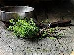 Thyme leaves tied together with string, vintage metal bowl and knife on rustic wooden surface