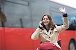 Young woman using wheelchair waving from city bus station