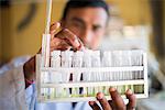 A lab technician working in a laboratory in a small hospital in Nepal holds a rack of test tubes, Jiri, Solu Khumbu, Nepal, Asia