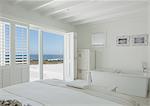 White hotel room with en suite soaking tub and ocean view