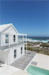 White beach house and swimming pool with ocean view under sunny blue sky