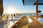 Sun shining over ocean behind luxury patio dining table with placesettings