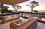 Modern luxury home showcase patio and swimming pool overlooking ocean view at sunset