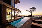 Modern luxury home showcase patio and swimming pool with sunset ocean view