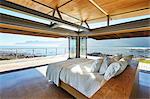 Modern luxury bed open to patio with sunny ocean view