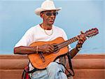 Cuba, Sancti Spiritus Province, Trinidad.  A street musician plays his guitar to passers by.