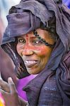 Niger, Agadez, Dabous. A Tuareg woman with painted patterns on her face. Her head scarf is coloured with indigo-blue.