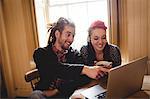 Smiling couple using laptop while sitting at table
