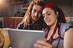 Young hipster couple using digital tablet while sitting in home
