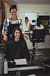 Smiling female hairdresser working on the client in hair salon