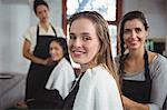 Portrait of smiling hairdresser working on the client at the hair salon