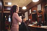 Female barber styling customer hair in barber shop