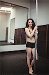 Portrait of pole dancer holding pole in fitness studio